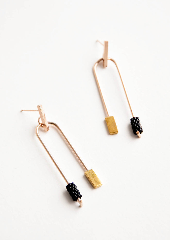 Post back gold earrings with curved arc featuring one black beaded end and one square gold end.
