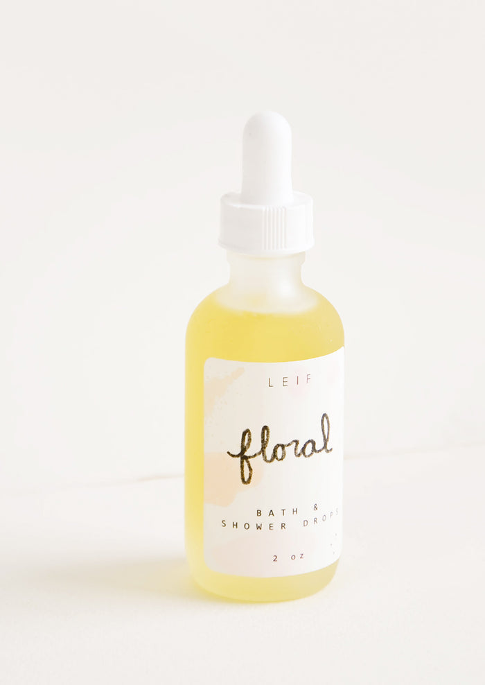A small frosted glass dropper bottle with a white lid and label reading "floral" filled with a pale yellow liquid.