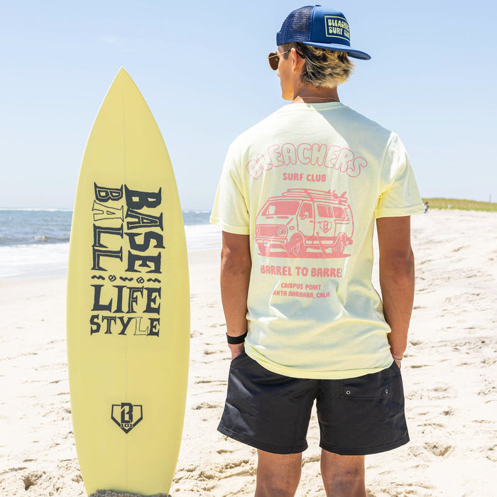 Adult model wearing yellow graphic tee with "Bleachers Surf Club" design