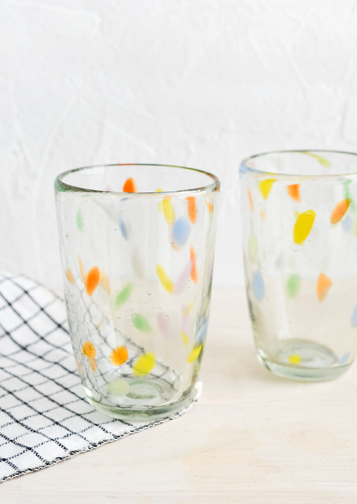 Two clear glass cups with flecks of color throughout.