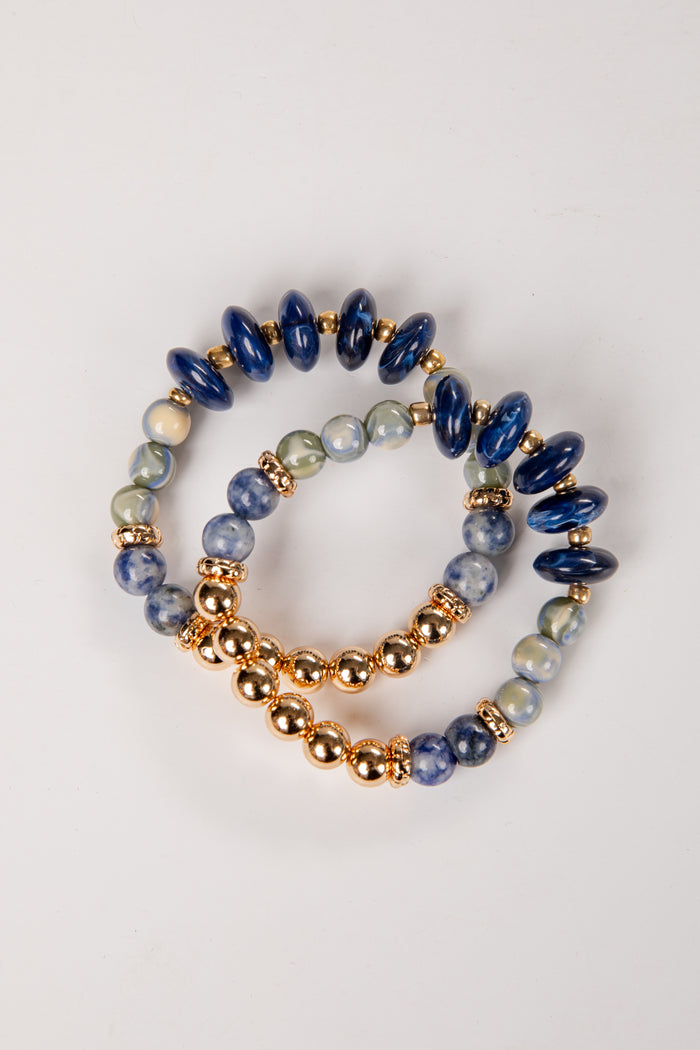 Three beaded bracelets with blue, gold, and multicolored beads on a white background