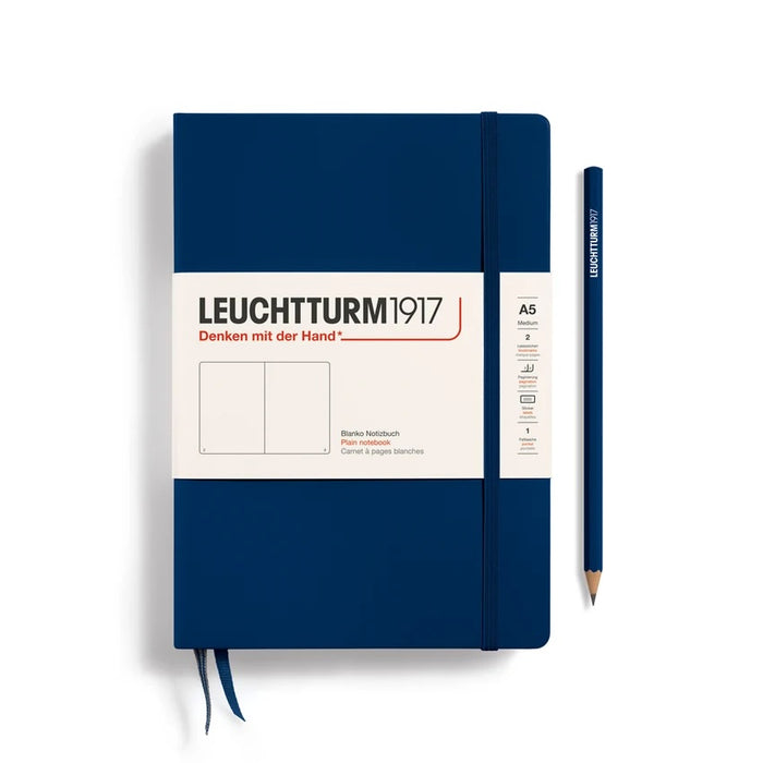 A Leuchtturm1917 A5 hardcover notebook in navy with a paper band around the middle, shown closed with a matching navy elastic closure and ribbon bookmark.