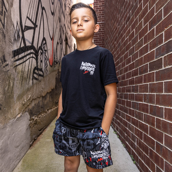 Youth model wearing gray youth shorts with “Night Game Drip” design