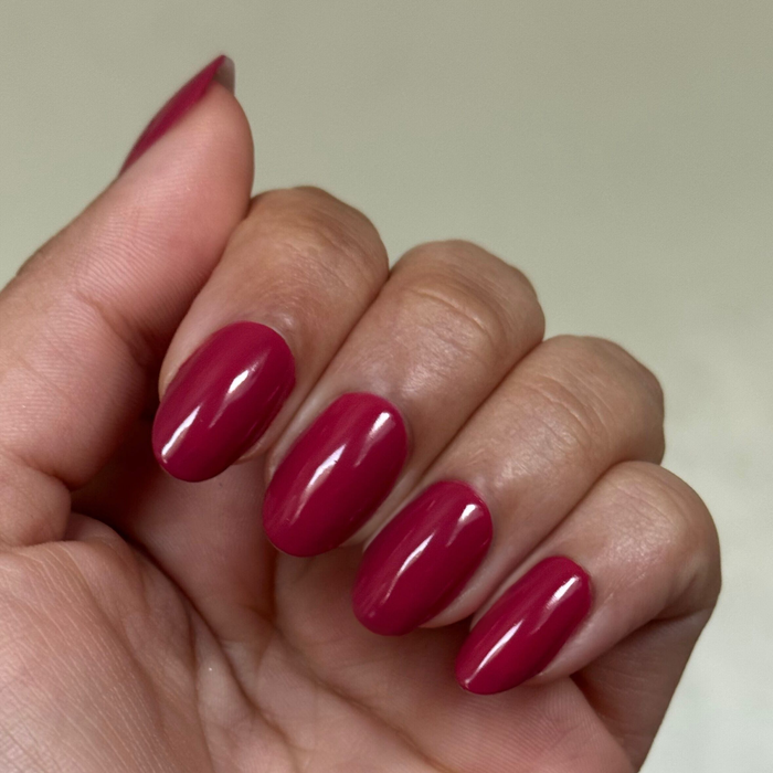 Hand with natural nails painted in glossy Roar gel polish showing a smooth, quick dry mani on neutral background