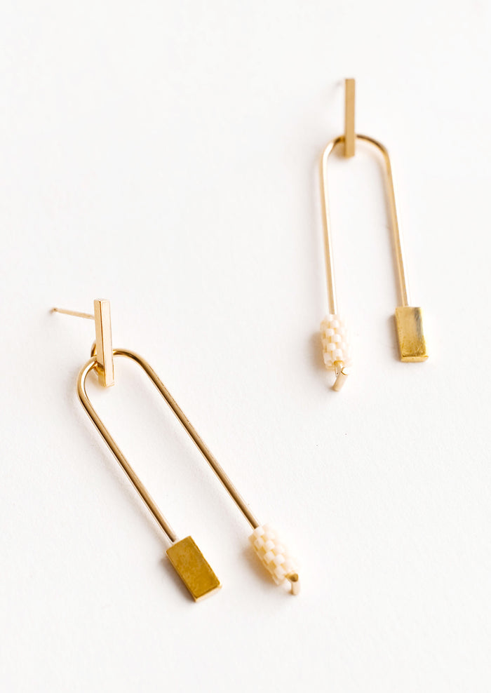 Post back gold earrings with curved arc featuring one cream color beaded end and one square gold end.