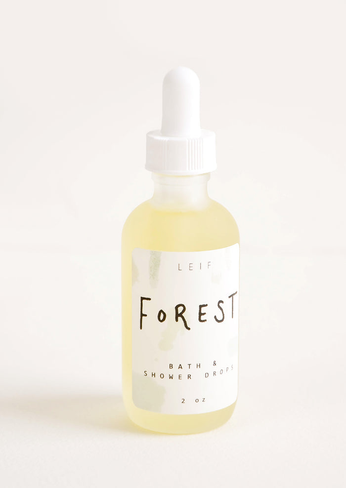 A small frosted glass dropper bottle with a white lid and a label reading "forest" filled with a pale yellow liquid.