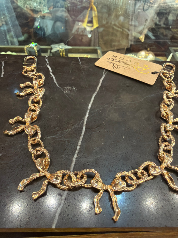 Joia bag chain charm with gold-tone links attached to a stylish handbag, showcasing its elegant accessory design.