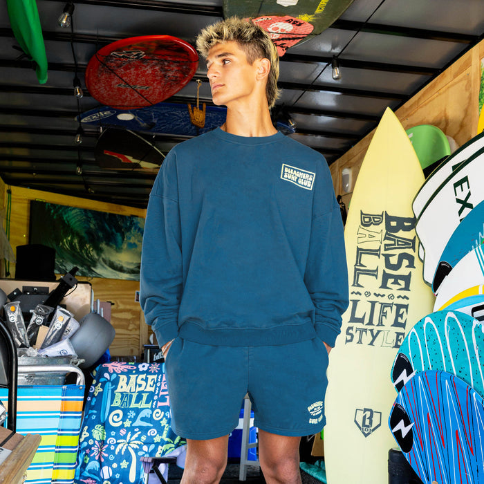 Adult model wearing blue shorts with "Bleachers Surf Club" design