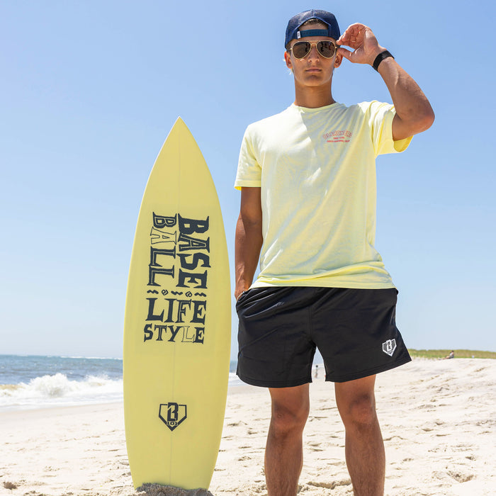 Adult model wearing yellow graphic tee with "Bleachers Surf Club" design