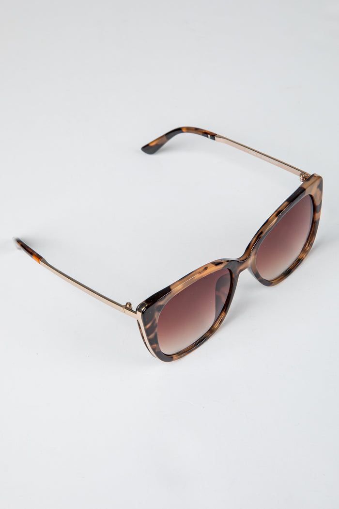 Sunglasses with tortoiseshell frame and brown gradient lenses on a white background