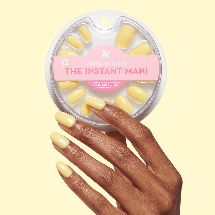 Bright & Focused | Round | Short bright yellow short round press-on nails shown on hand with package on pale yellow background