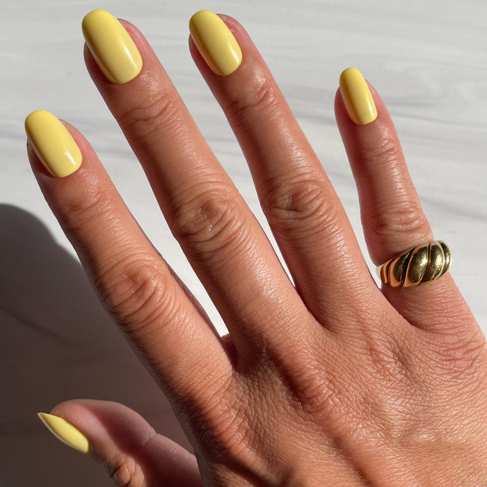 Bright & Focused | Round | Short yellow press-on nails in short round shape with a smooth glossy finish on hand in natural light