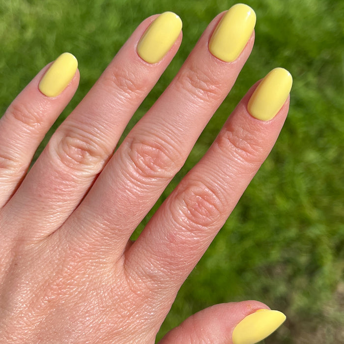 Bright & Focused | Round | Short yellow press-on nails in short round shape with smooth glossy finish shown on hand outdoors