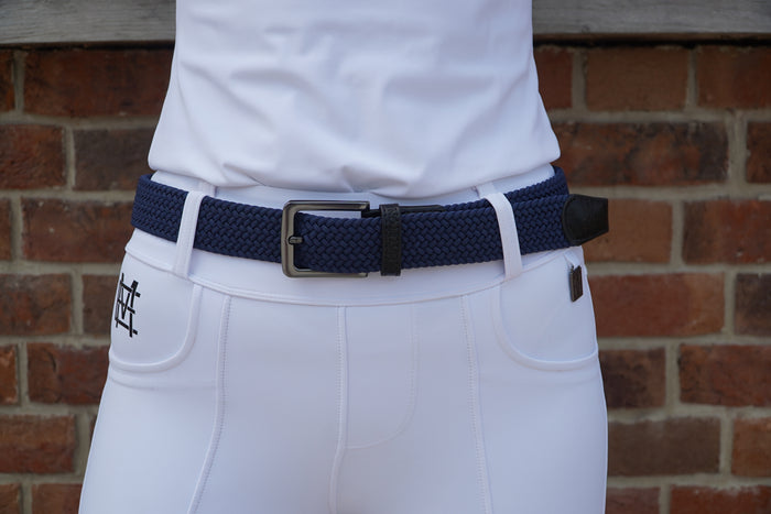 White pants with a navy belt and black buckle against a brick wall. Elastic stretch quality belt for casual or riding wear