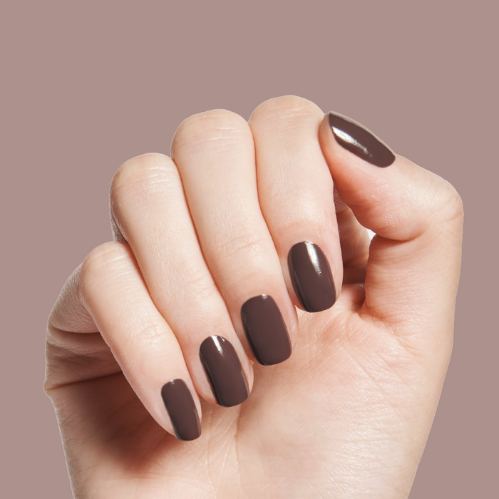 Bunny deep neutral brown gel polish shown on medium length nails against warm taupe background