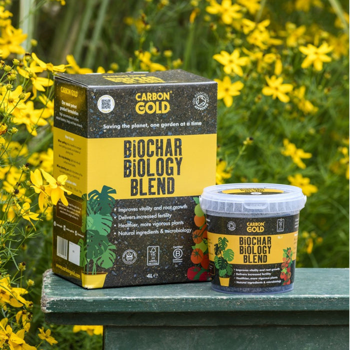 A package and a container of Carbon Gold Biochar Biology Blend, placed on a surface with yellow flowers in the background.