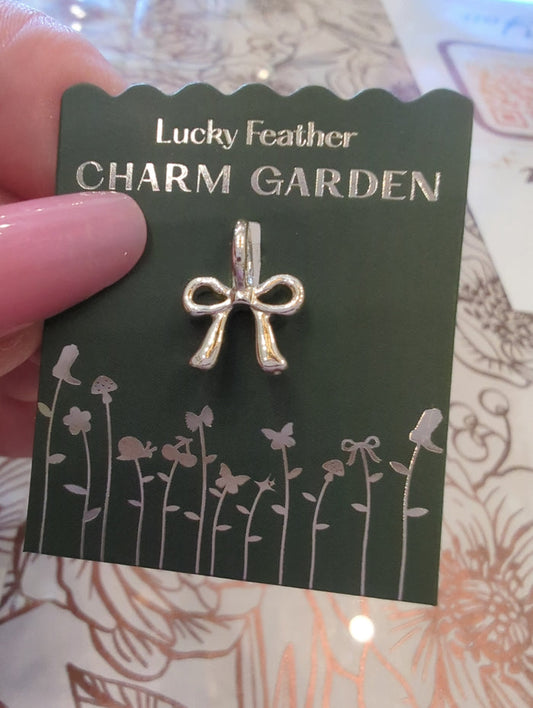 Silver bow charm from Lucky Feather's Charm Garden collection, featuring a delicate, detailed silver charm.