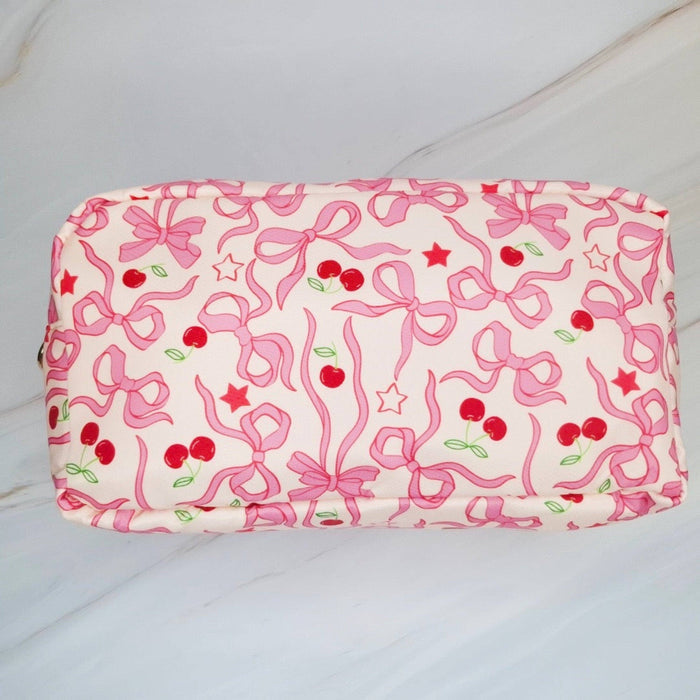 Cherry Bowtiful cosmetic bag by Ellison+Young featuring a cherry pattern, compact design, and zipper closure for everyday use.