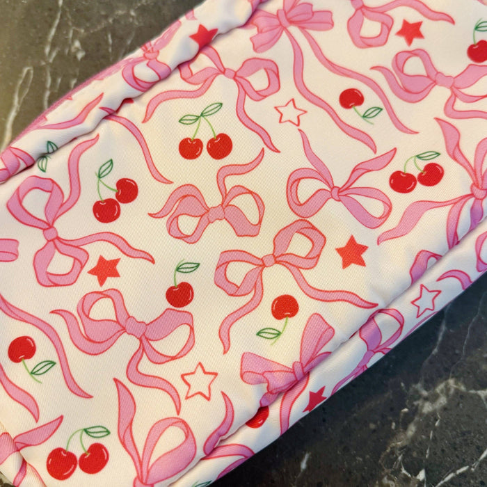 Ellison+Young Cherry Bowtiful everyday cosmetic case in pink with bow detail, compact bag for makeup and small essentials.