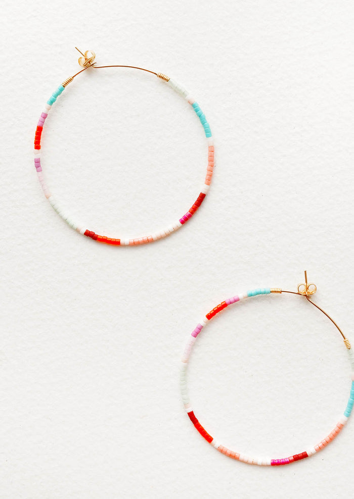 Delicate beaded hoop earrings of blue, orange, pink, white, and red glass beads on thin gold wire.