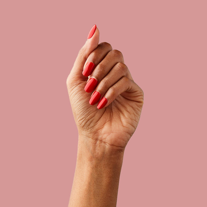 CV - Press-On | Short | Round showing hand with bright cherry red short round press-on nails against pink background