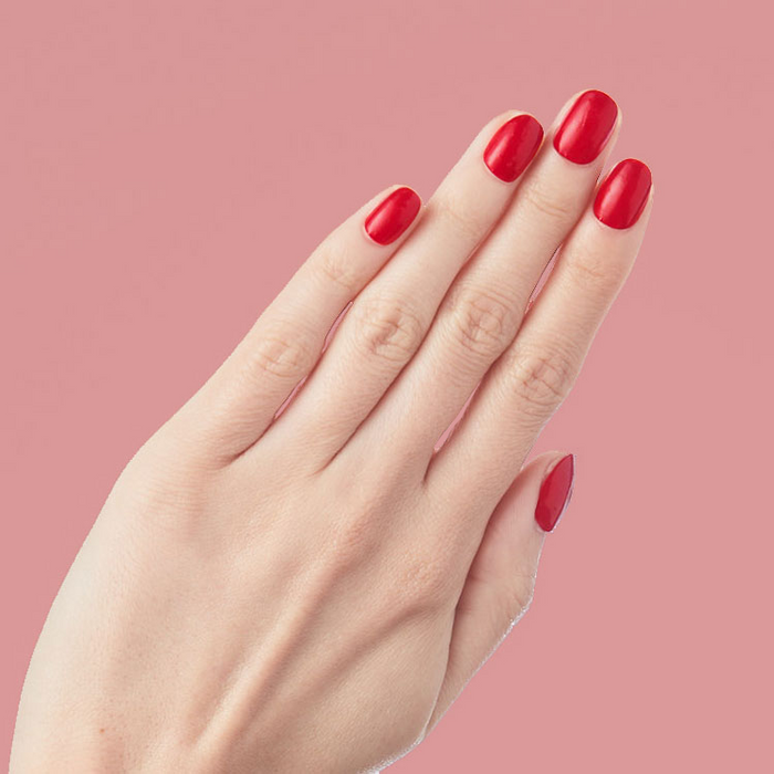 CV - Press-On | Short | Round showing hand with short round cherry red press-on nails against soft pink background