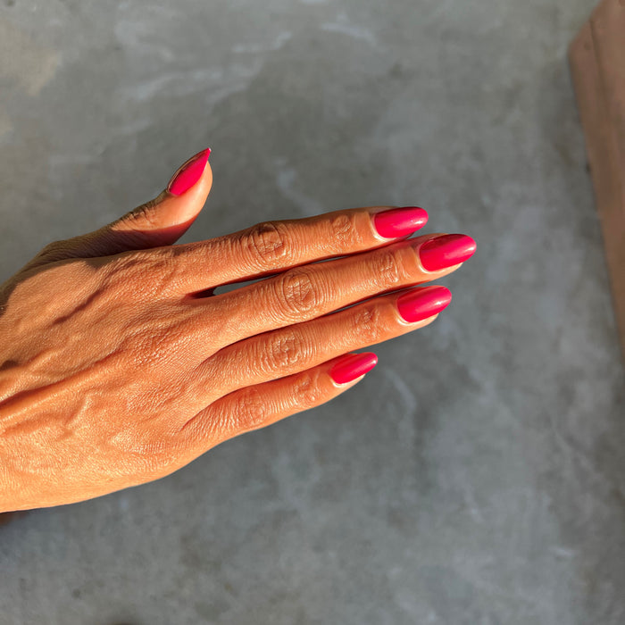 CV - Press-On | Short | Round showing hand with short round nails in bright cherry red press-on manicure outdoors