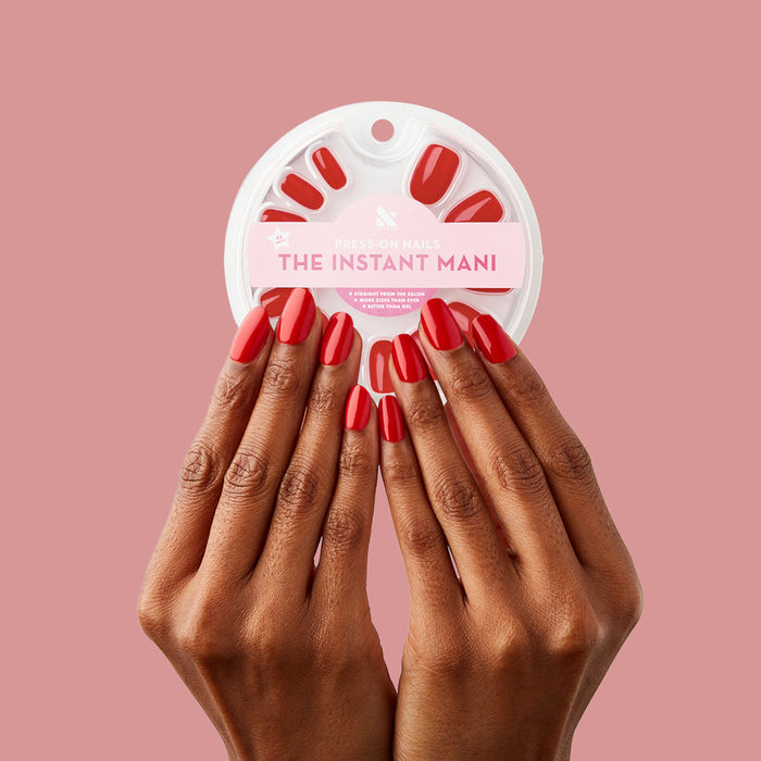 CV - Press-On | Short | Round showing hands with short round cherry red press-on nails holding circular press-on nail pack