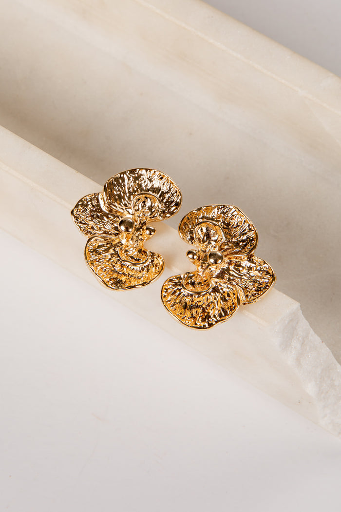 Gold earrings on a white fabric background