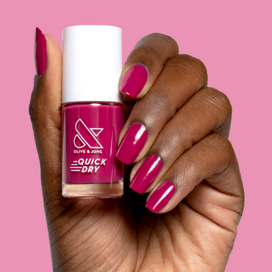 Hand holding Darling quick dry gel polish bottle with matching vibrant hot magenta mani on natural nails