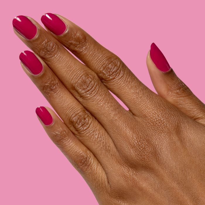 Hand with natural nails painted in glossy Darling gel polish hot magenta showing a quick dry at home manicure