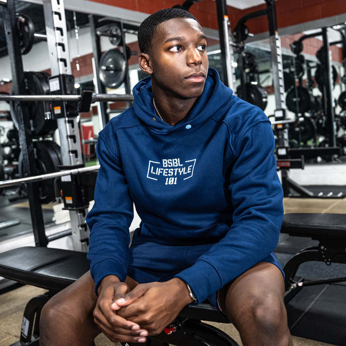 Person wearing a blue hoodie with 'BSBL Lifestyle 101' logo in a gym setting