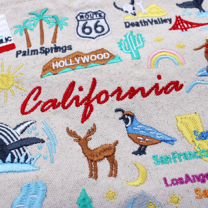 Cream canvas tote fabric with colorful embroidered California script and landmarks
