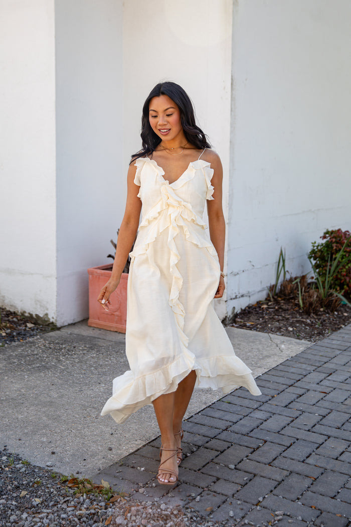 Woman in a white dress walking outdoors on a sunny day.