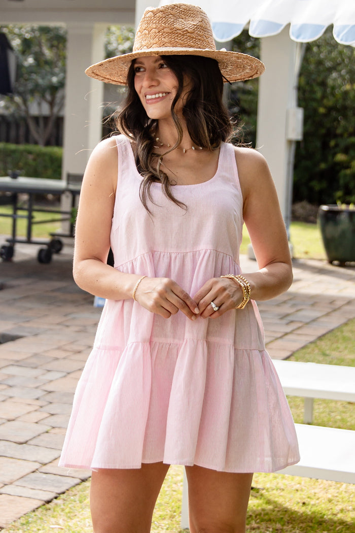 Woman wearing a pink dress and straw hat outdoors