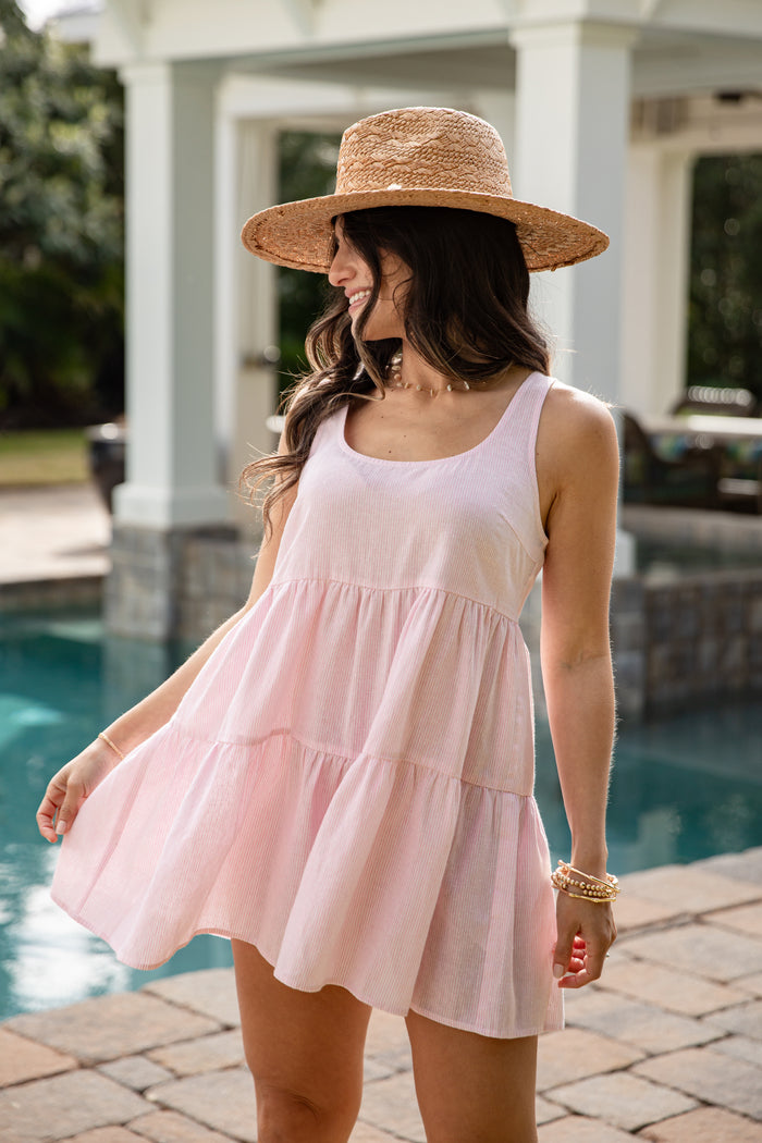 Woman in a pink dress and straw hat by a pool
