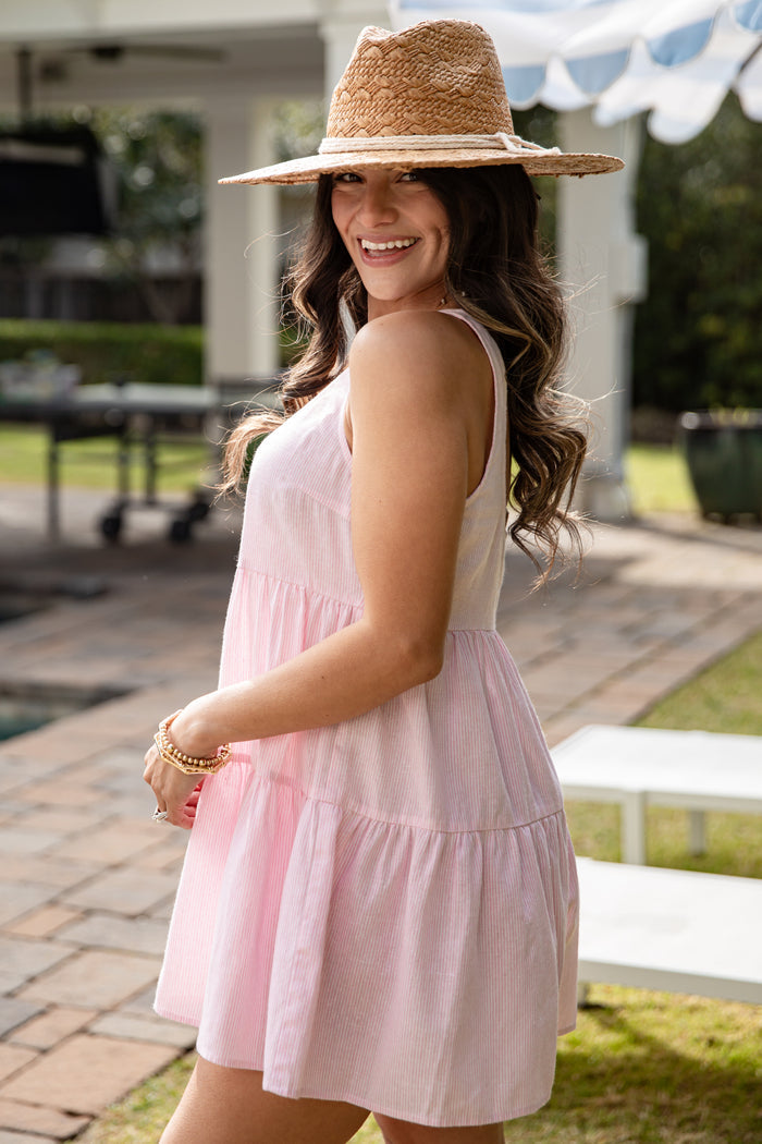Woman wearing a pink dress and straw hat outdoors