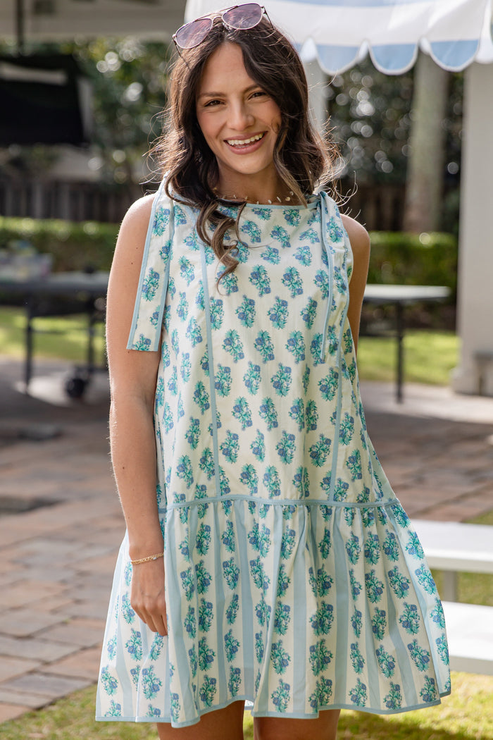 Woman wearing a floral dress standing outdoors under a canopy.