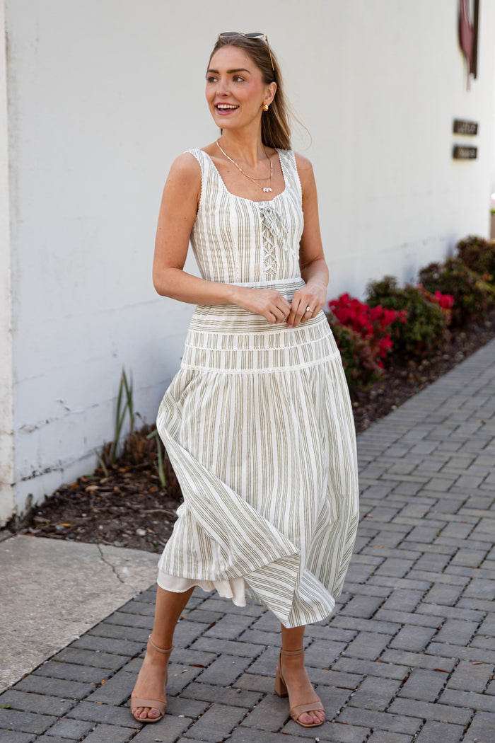 Woman wearing a spring striped maxi dress with sunglasses and nude heels