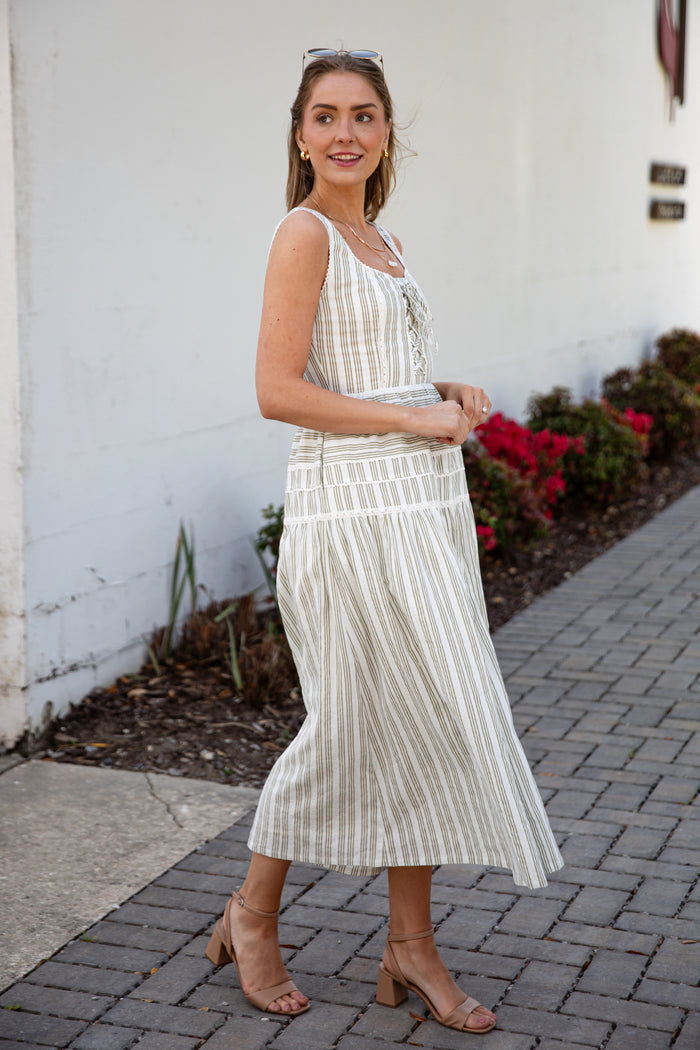 Woman wearing a spring striped maxi dress with sunglasses and nude heels