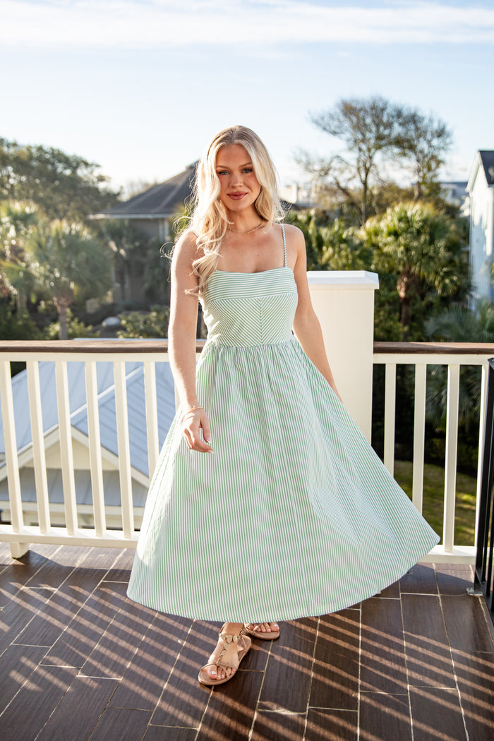 Woman in a light green dress standing on a balcony with a scenic background