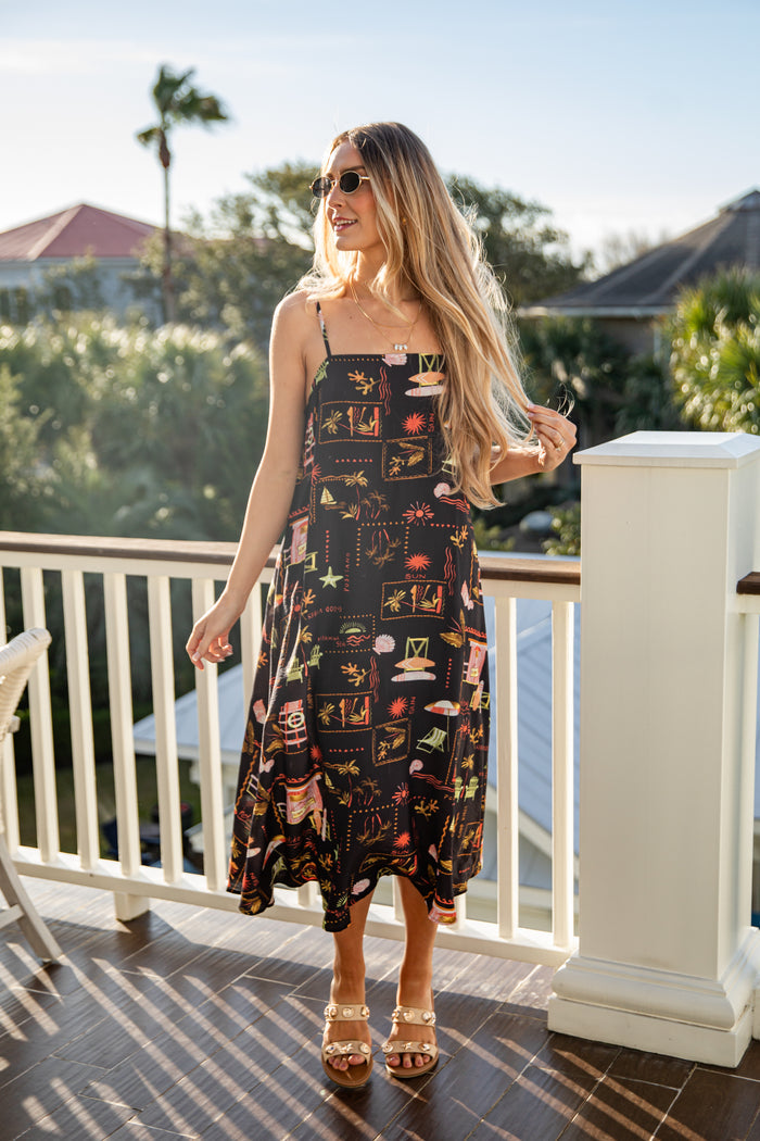 Woman in a patterned dress standing on a balcony with a scenic background
