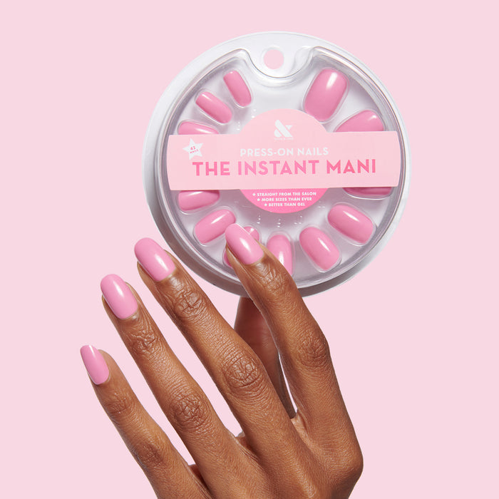 Hand with short round pink press-on nails holding Grateful & Kind | Round | Short set for easy at-home manicure