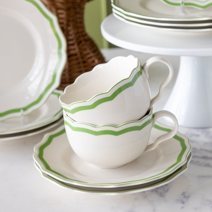 White teacup and saucer with green stripes on a marble surface.