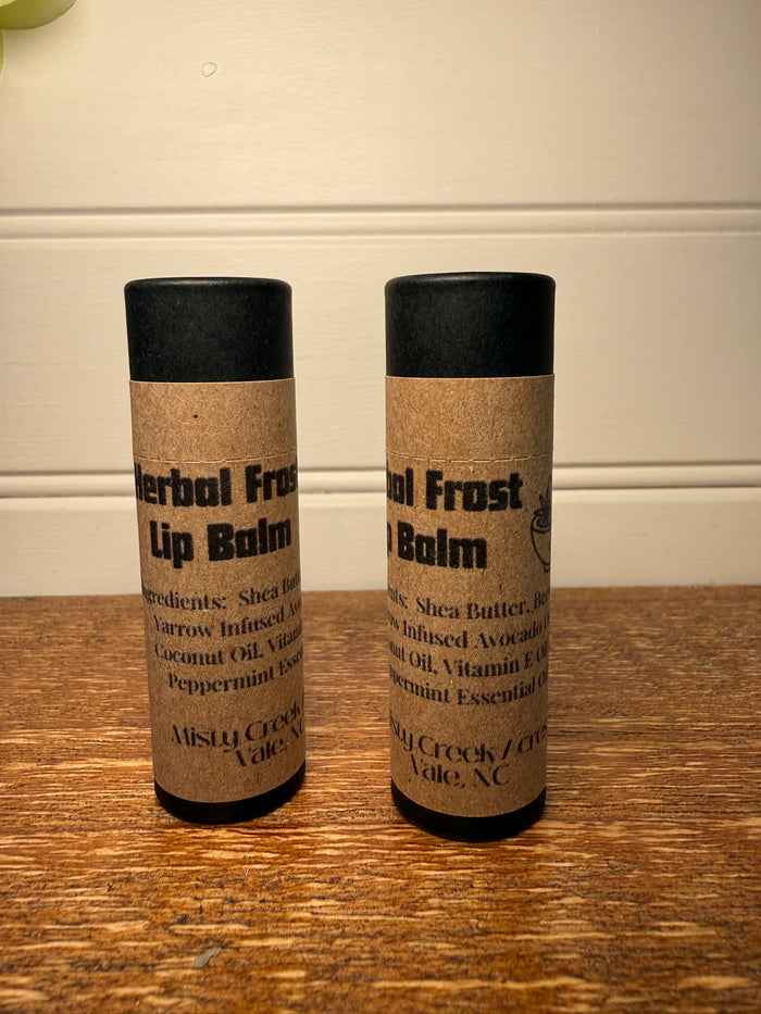 Two lip balm containers on a wooden surface with a neutral background