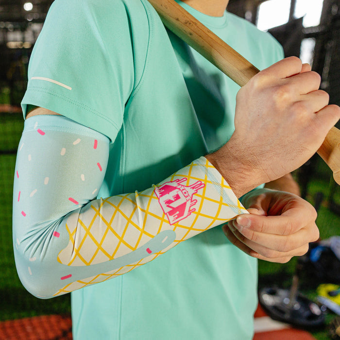 Close-up of the cotton candy ice cream arm sleeve on a player's arm showing the light blue sprinkle print waffle cone design and pink BL101 logo near the wrist
