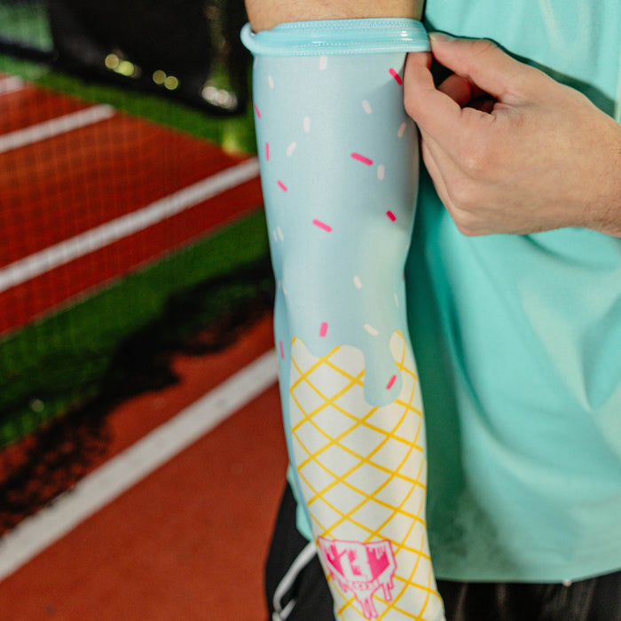 Close-up of the cotton candy ice cream arm sleeve being pulled up at the bicep showing the light blue elastic band and sprinkle print against a mint green shirt