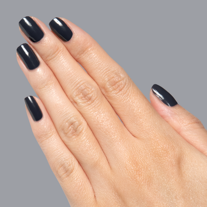 Hand with natural nails painted in deep charcoal Inkling gel polish showing a sleek quick dry mani on neutral background