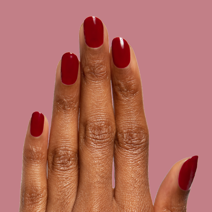 Jammy deep sheer cabernet gel polish on natural nails with a glossy quick dry finish against muted pink background