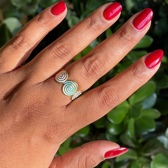 Jammy bright sheer cabernet gel polish on natural nails with glossy finish and spiral gold ring outdoors